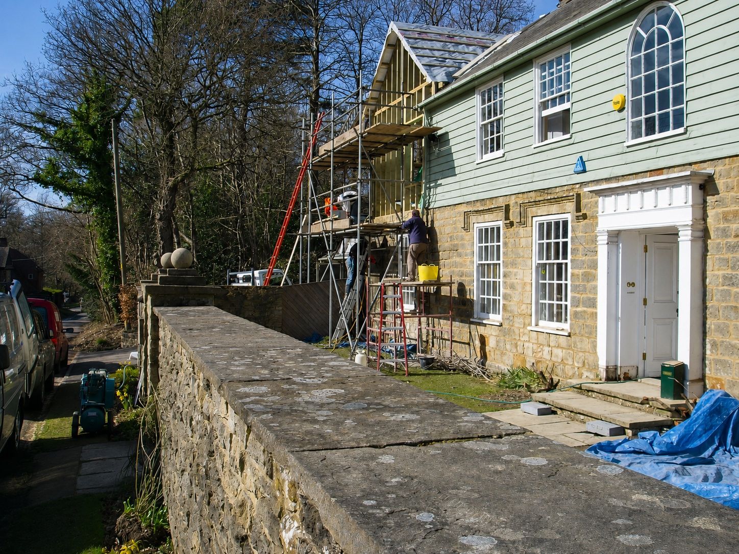 Timber-framed extension being built onto a stone and timber-clad house